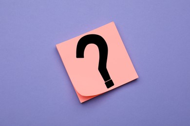 Photo of Sticky note with question mark on violet background, top view