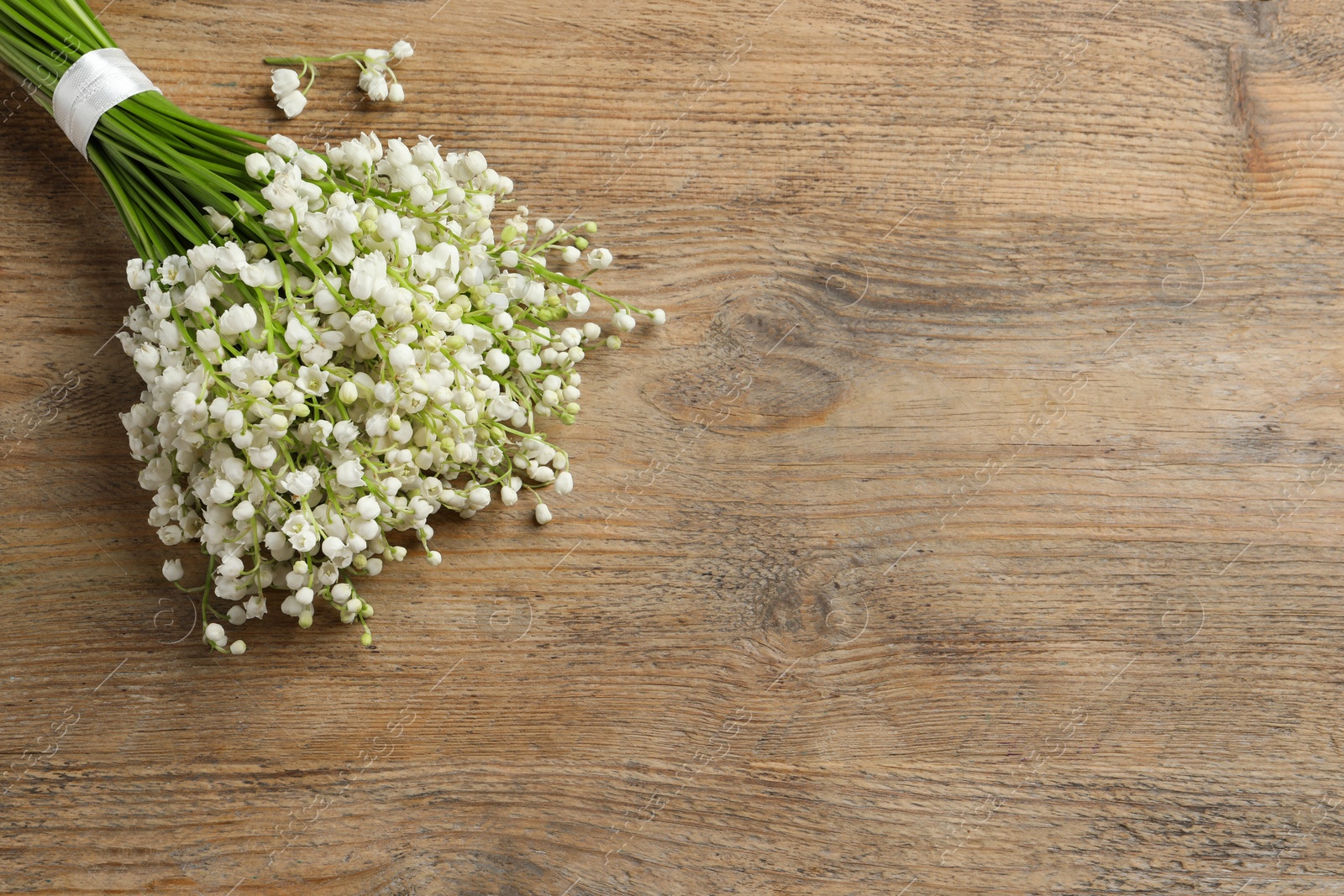 Photo of Beautiful lily of the valley bouquet on wooden table, top view. Space for text