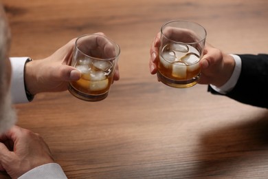 Men with glasses of whiskey at wooden table, closeup