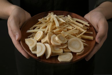 Photo of Woman holding plate with cut parsnips, closeup