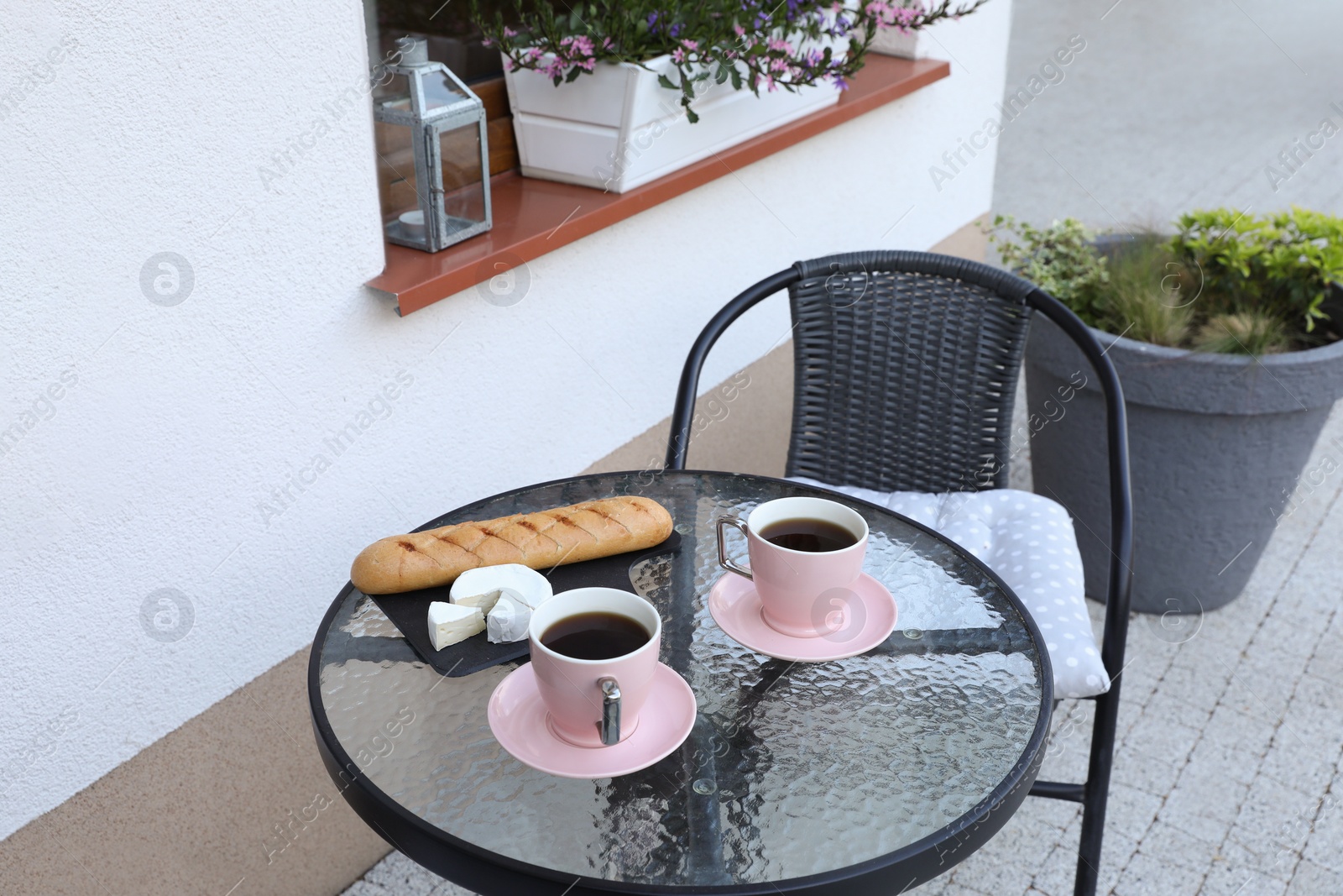 Photo of Cups of coffee, bread and cheese on glass table. Relaxing place at outdoor terrace