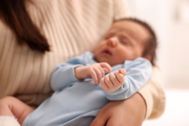 Photo of Mother with her sleeping newborn baby on blurred background, selective focus