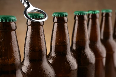 Opening bottle of beer on light brown background, closeup. Space for text