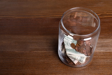 Donation jar with money on wooden background. Space for text