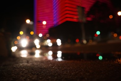 View of cityscape with bokeh effect, focus on asphalt. Night life
