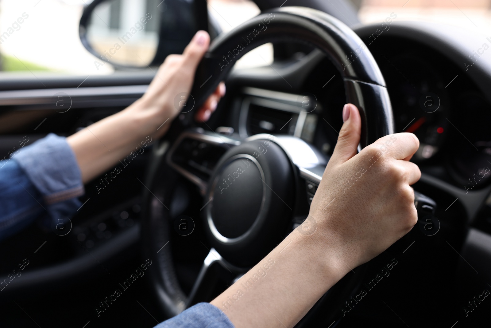 Photo of Woman holding steering wheel while driving her car, closeup