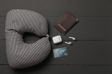 Photo of Striped travel pillow, passport, credit card and earphones on black wooden background, flat lay. Space for text