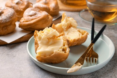 Photo of Delicious profiterole filled with cream on grey table, closeup