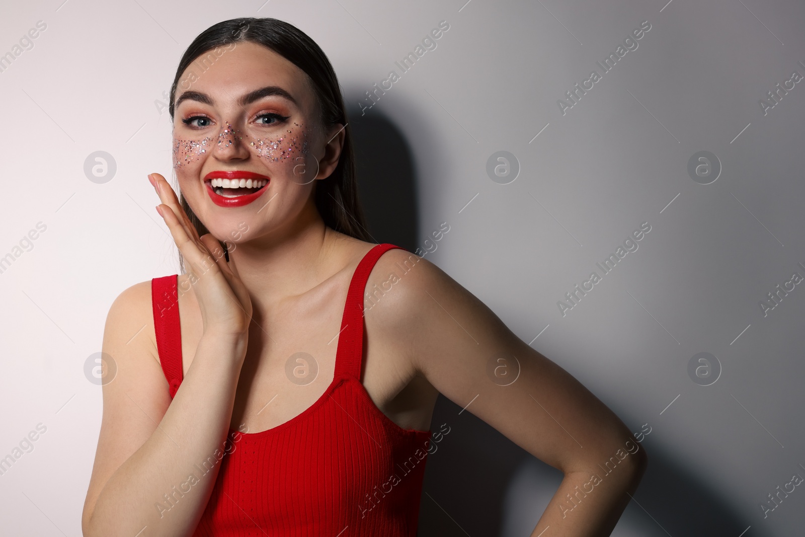 Photo of Happy woman with glitter freckles on light background. Space for text