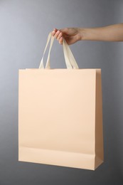 Photo of Woman holding paper bag on grey background, closeup. Mockup for design