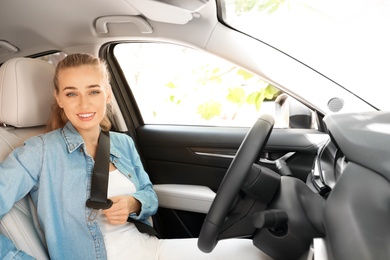 Female driver fastening safety belt in car