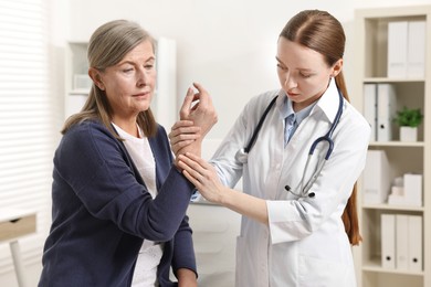 Arthritis symptoms. Doctor examining patient's hand in hospital