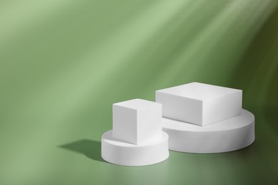 Photo of Product presentation scene. Podiums of different geometric shapes on pale light green background, space for text