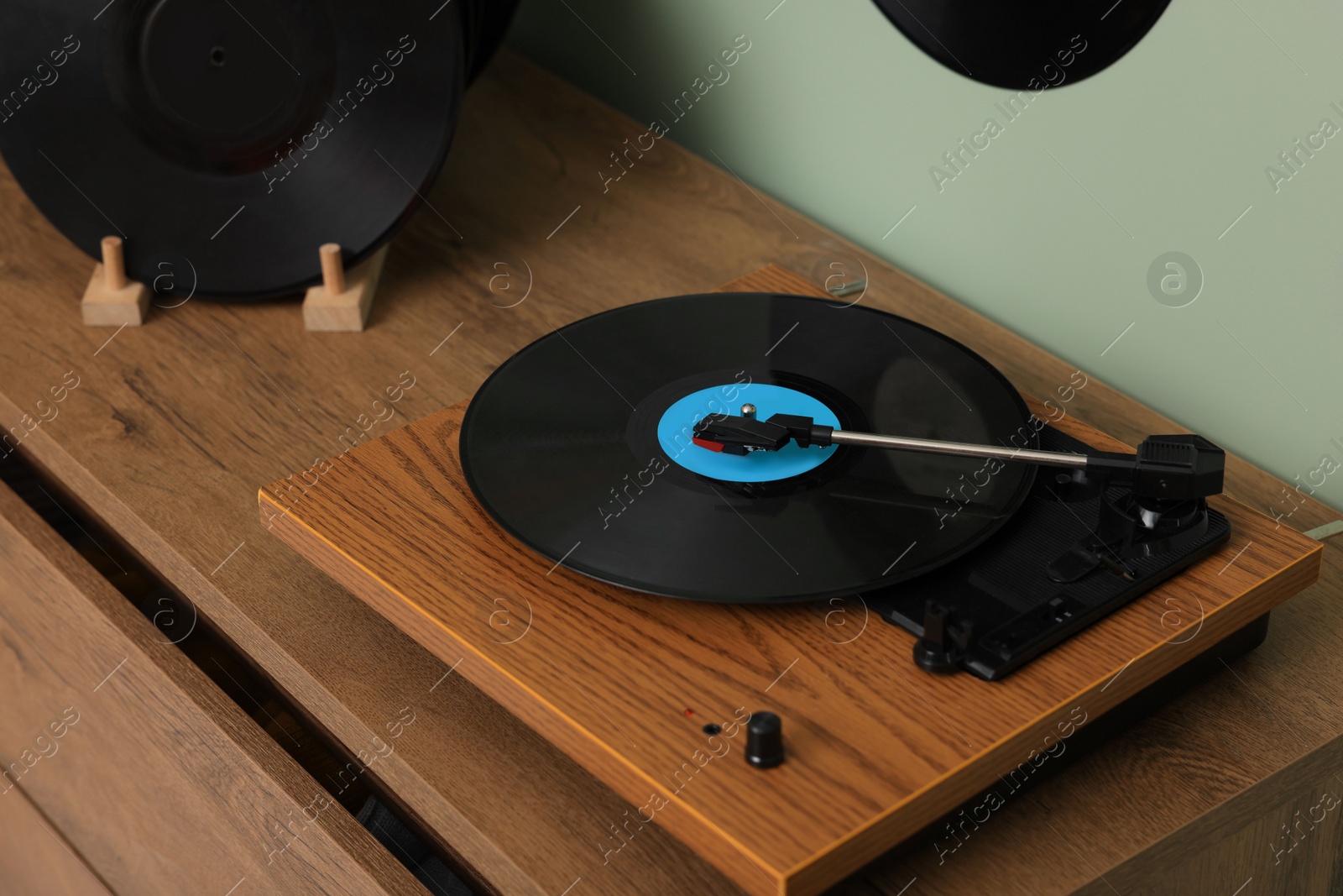Photo of Vinyl record player on wooden chest of drawer indoors