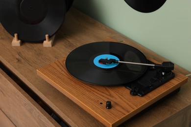 Photo of Vinyl record player on wooden chest of drawer indoors