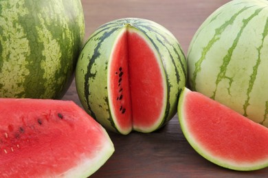 Photo of Different delicious ripe watermelons on wooden table