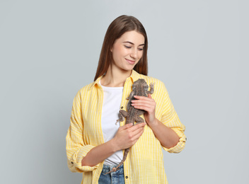 Woman holding bearded lizard on grey background. Exotic pet