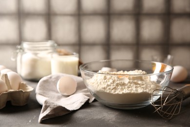 Making dough. Flour with in bowl and whisk on grey textured table, closeup