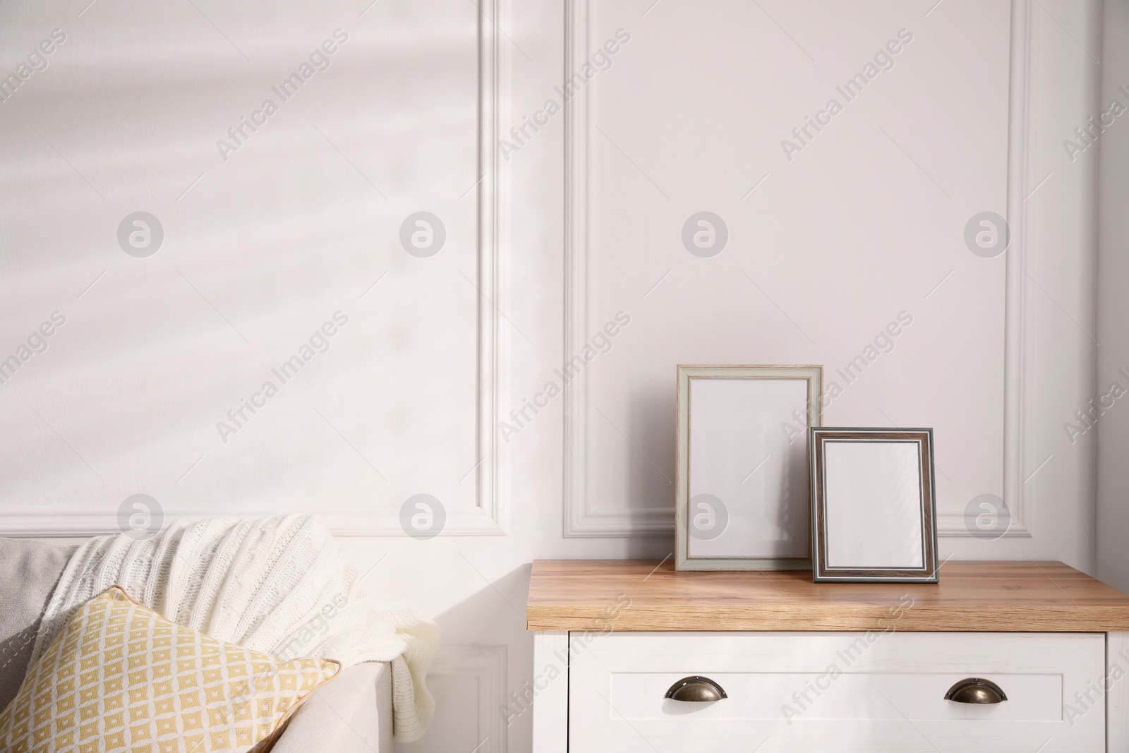 Photo of Empty photo frames on chest of drawers in living room, space for text