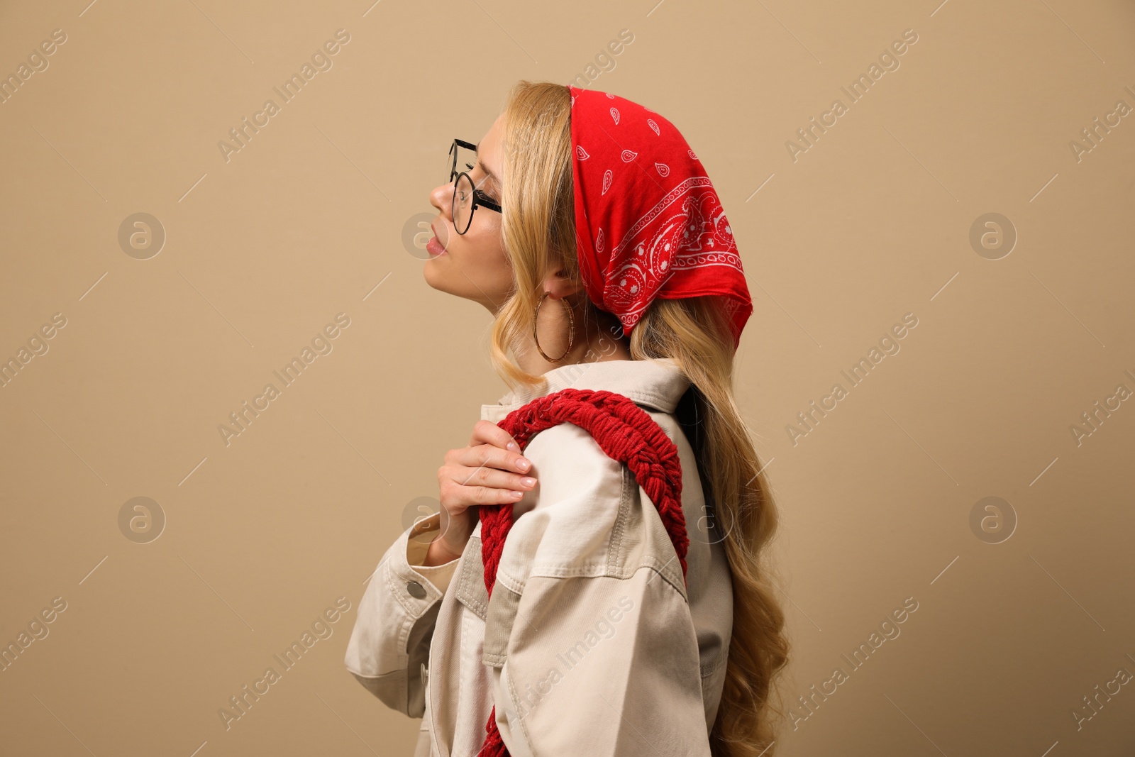 Photo of Young woman with stylish bandana on beige background