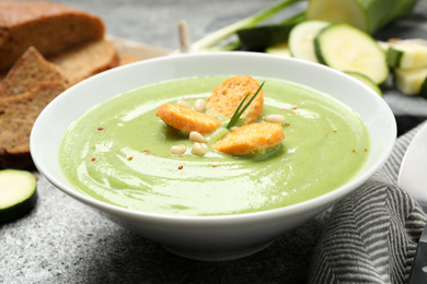 Photo of Tasty homemade zucchini cream soup served on grey table