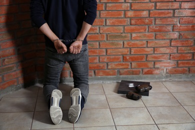 Male drug dealer in handcuffs near brick wall. Space for text