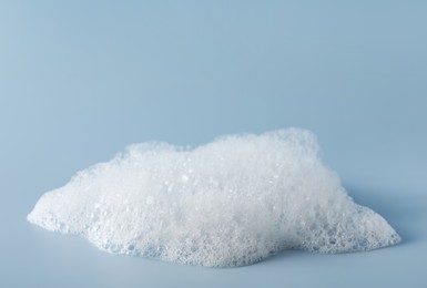 Photo of Fluffy bath foam on light blue background