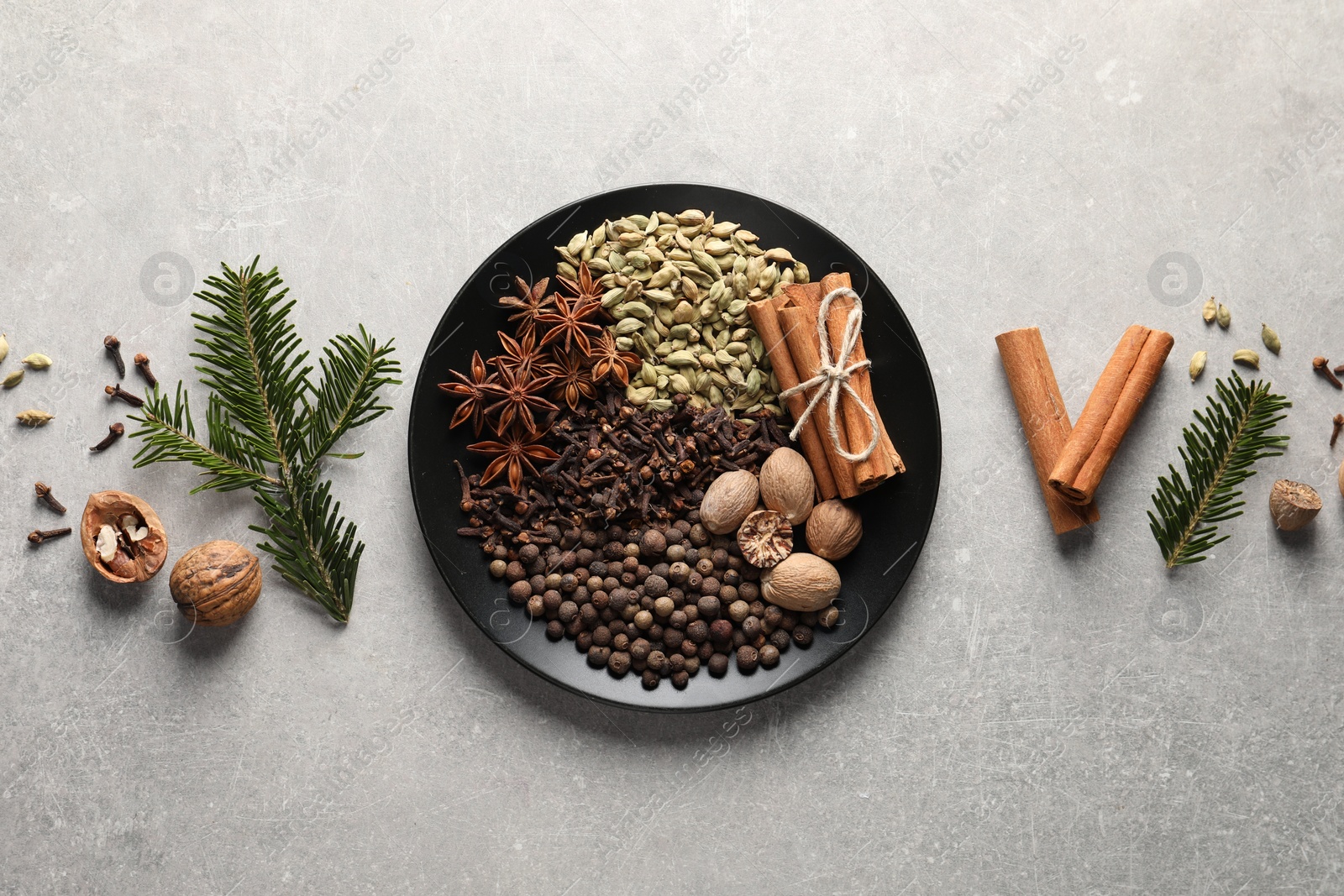 Photo of Different spices, nuts and fir branches on light gray textured table, flat lay