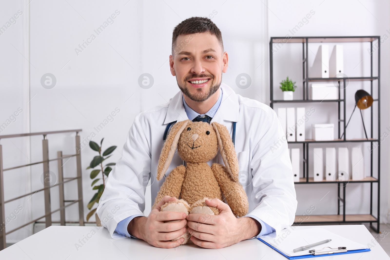 Photo of Pediatrician with toy bunny at desk in office