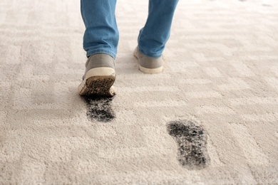 Photo of Person in dirty shoes leaving muddy footprints on carpet