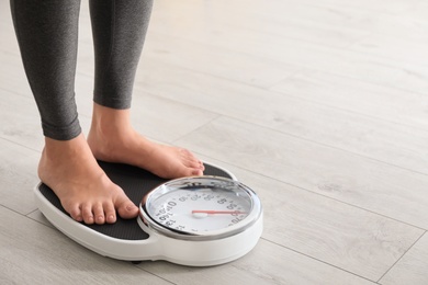 Photo of Woman standing on scales indoors, space for text. Overweight problem