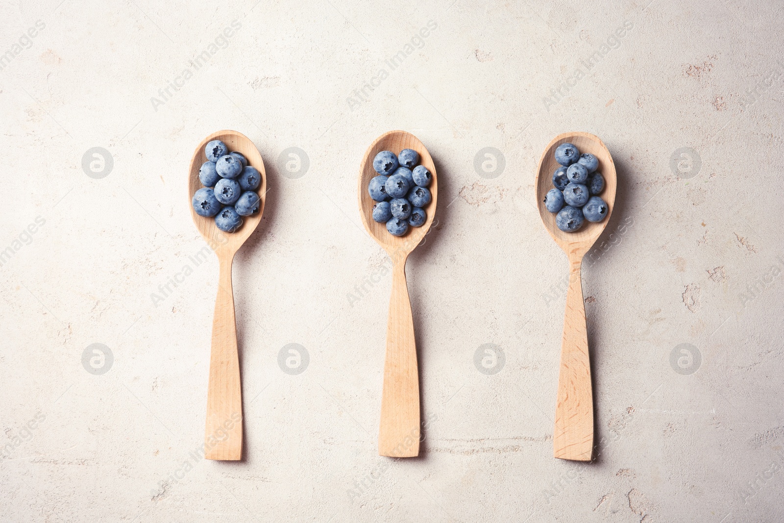 Photo of Flat lay composition with spoons and juicy blueberries on color table
