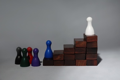 Photo of White chess piece on top of wooden stairs against grey background