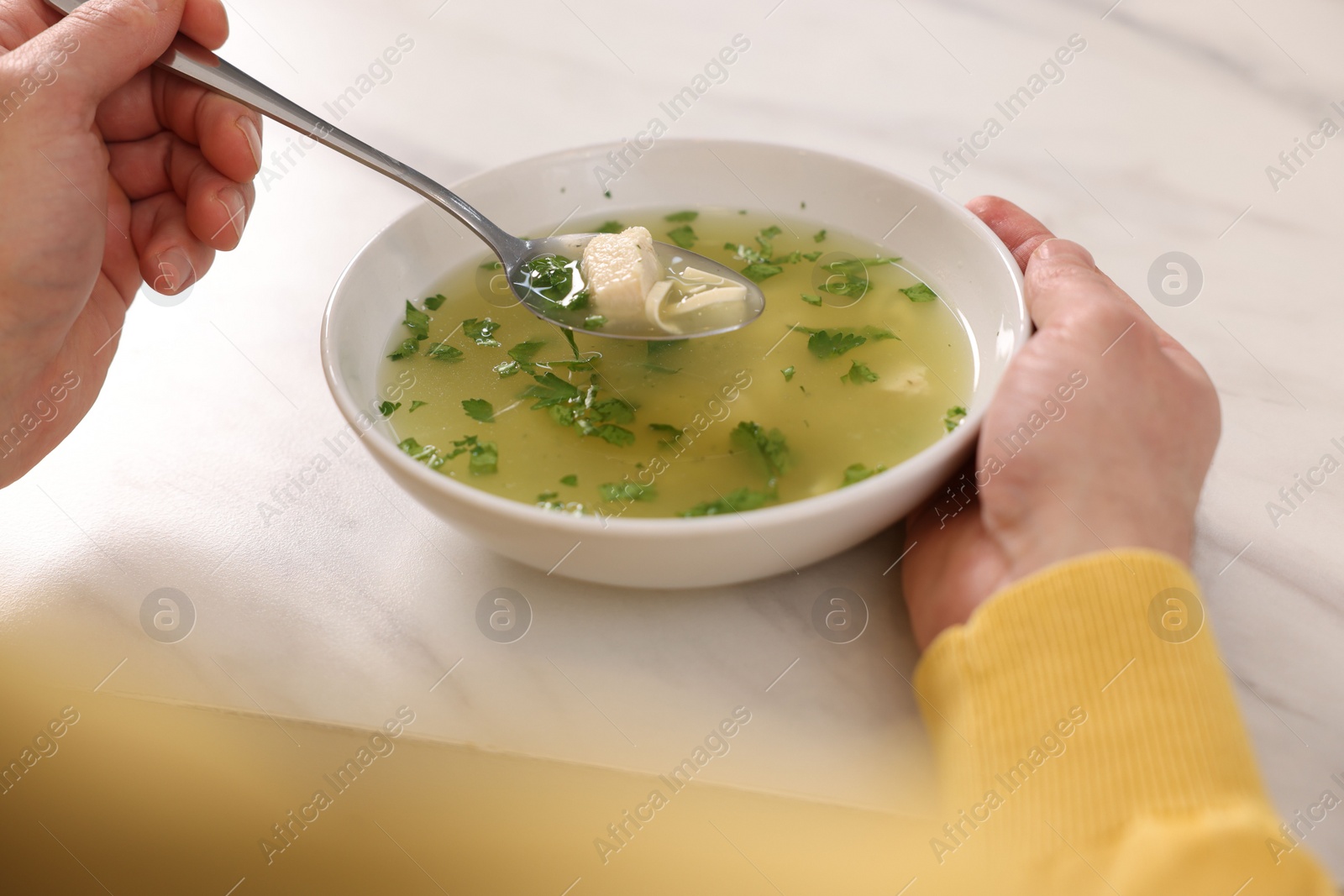 Photo of Man eating delicious chicken soup at light table, closeup