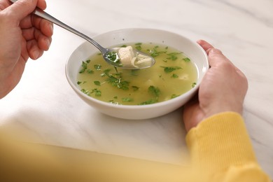Man eating delicious chicken soup at light table, closeup