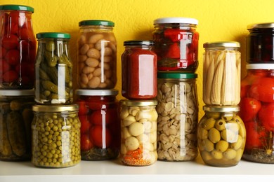 Photo of Jars of pickled vegetables on white wooden table
