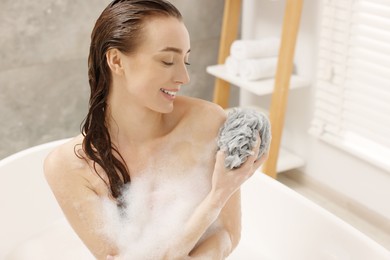 Photo of Woman taking bath with shower gel in bathroom