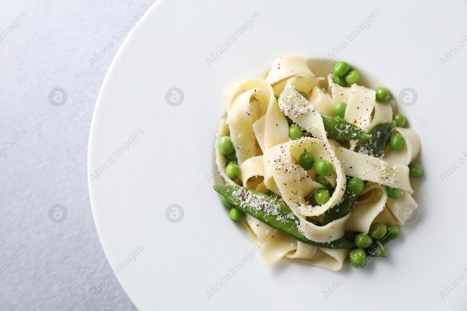 Photo of Delicious pasta with green peas on grey table, top view