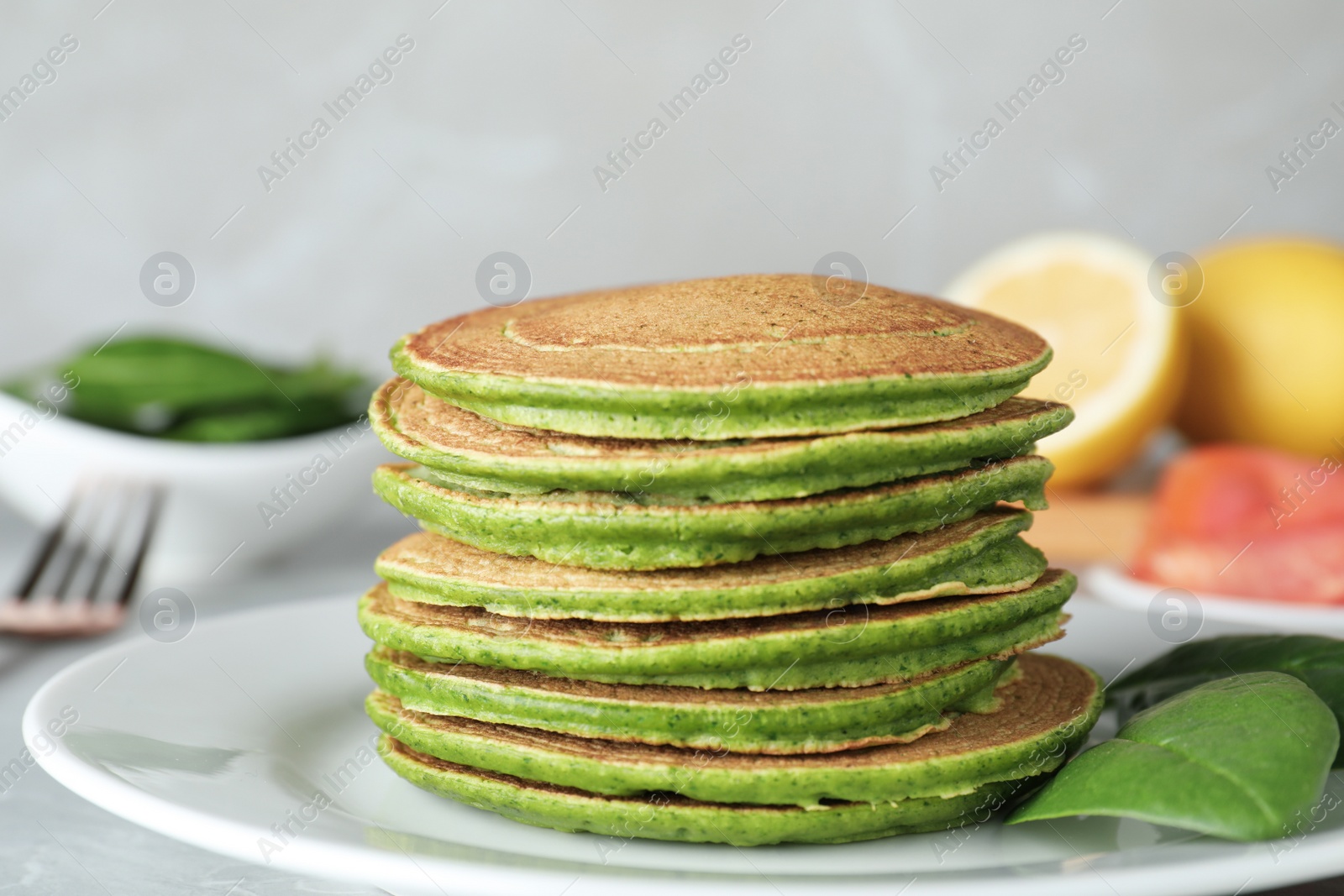 Photo of Tasty spinach pancakes on light grey table, closeup