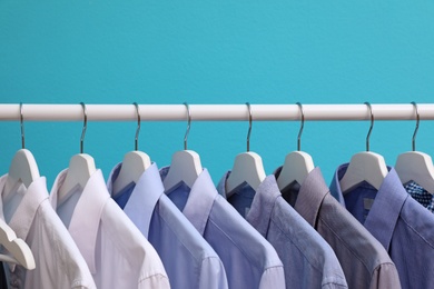 Photo of Wardrobe rack with men's clothes on color background