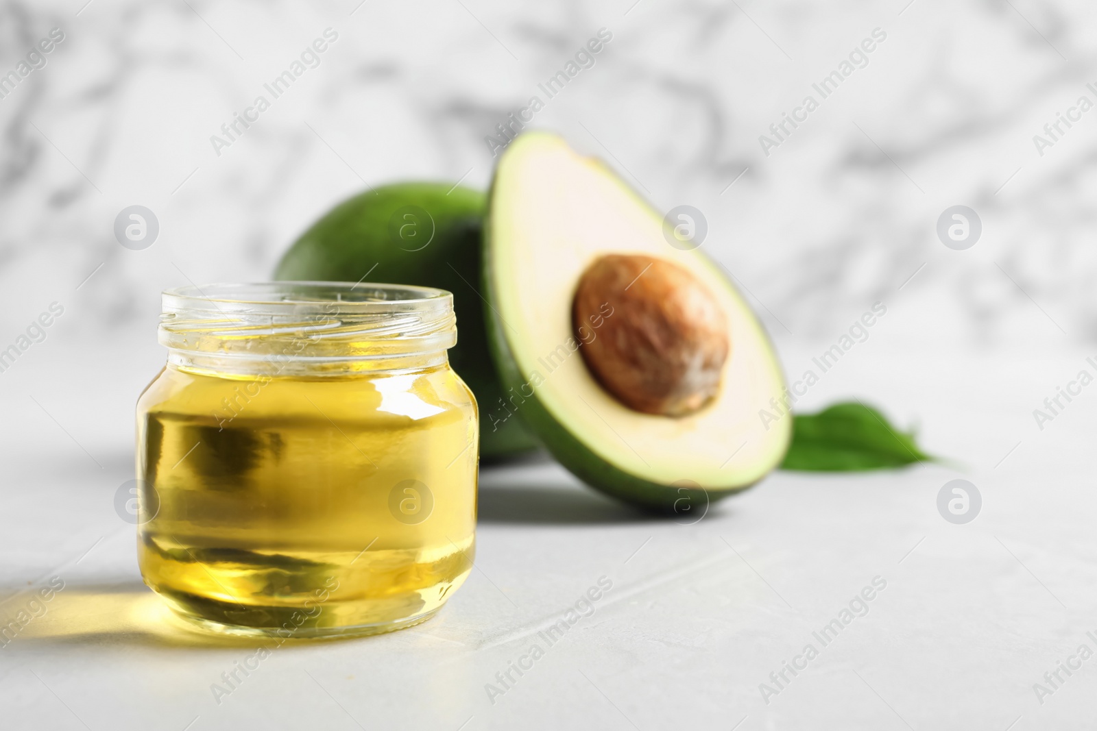 Photo of Jar with avocado oil on table