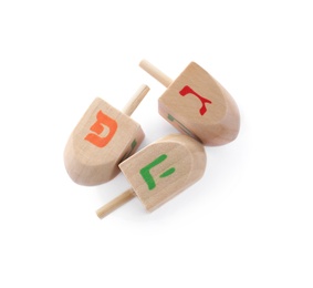 Photo of Wooden Hanukkah traditional dreidels with letters Gimel, Pe and He on white background, top view