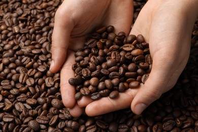 Woman with roasted coffee beans, closeup view