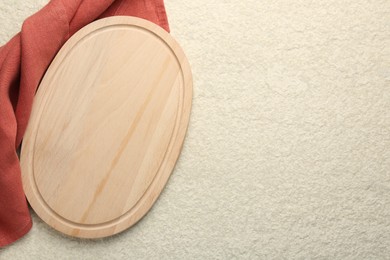 Wooden cutting board and cloth on beige table, top view. Space for text