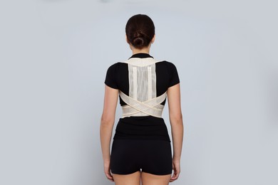 Photo of Woman with orthopedic corset on grey background, back view