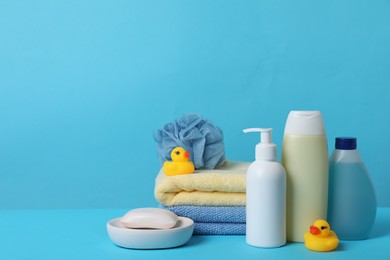 Baby cosmetic products, bath ducks, sponge and towels on light blue background. Space for text