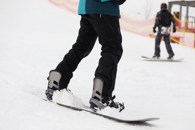 Photo of Snowboarder on slope at resort, closeup. Winter vacation