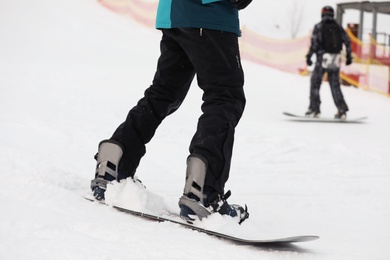 Snowboarder on slope at resort, closeup. Winter vacation