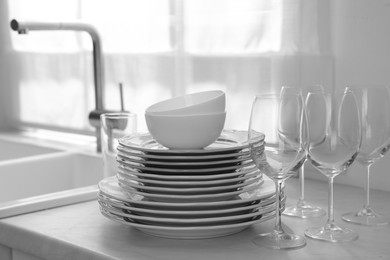 Photo of Different clean dishware and glasses on countertop near sink in kitchen