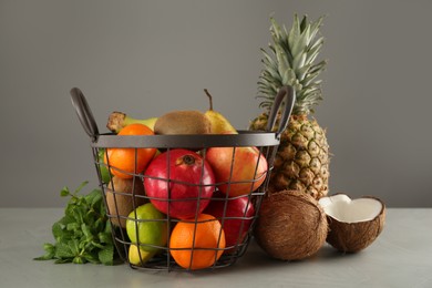 Photo of Metal basket and different ripe fruits on grey table